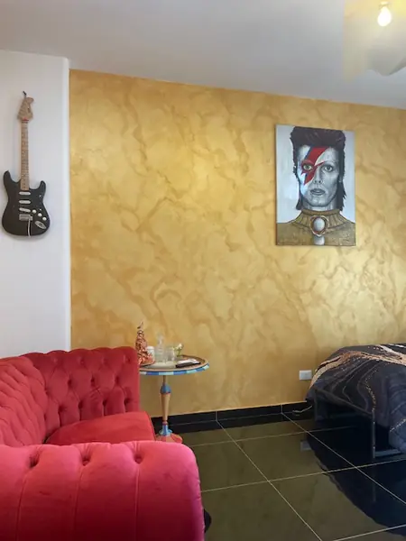 Monolocale Rock con parete dorata, ritratto di David Bowie e divano rosso