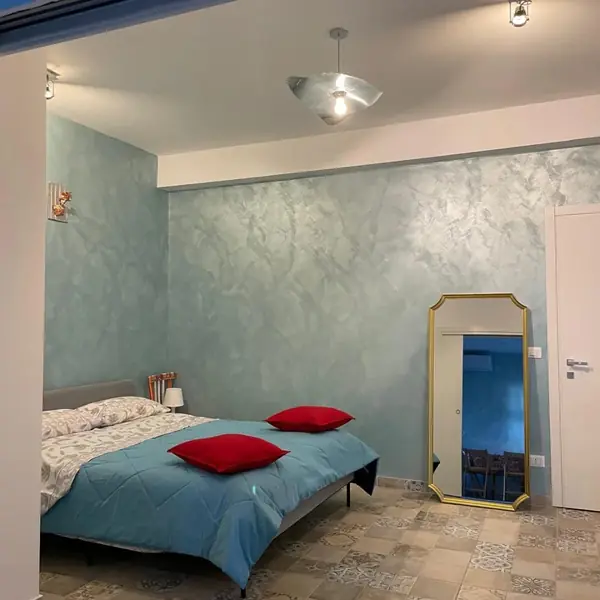 Letto matrimoniale del bilocale Sicilia con cuscini rossi e specchio dorato